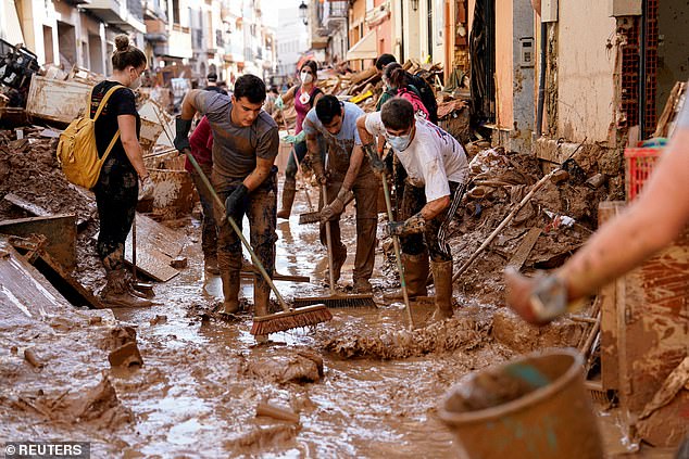 Volunteers and locals help to clean the mud off the street following heavy rains in Paiporta, near Valencia, Spain, November 5, 2024