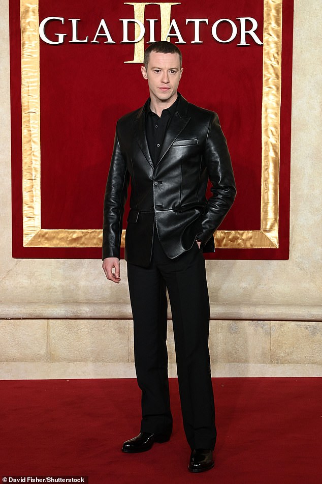 Joseph Quinn wore a black leather jacket paired with a black silk shirt and black mohair trousers by Prada