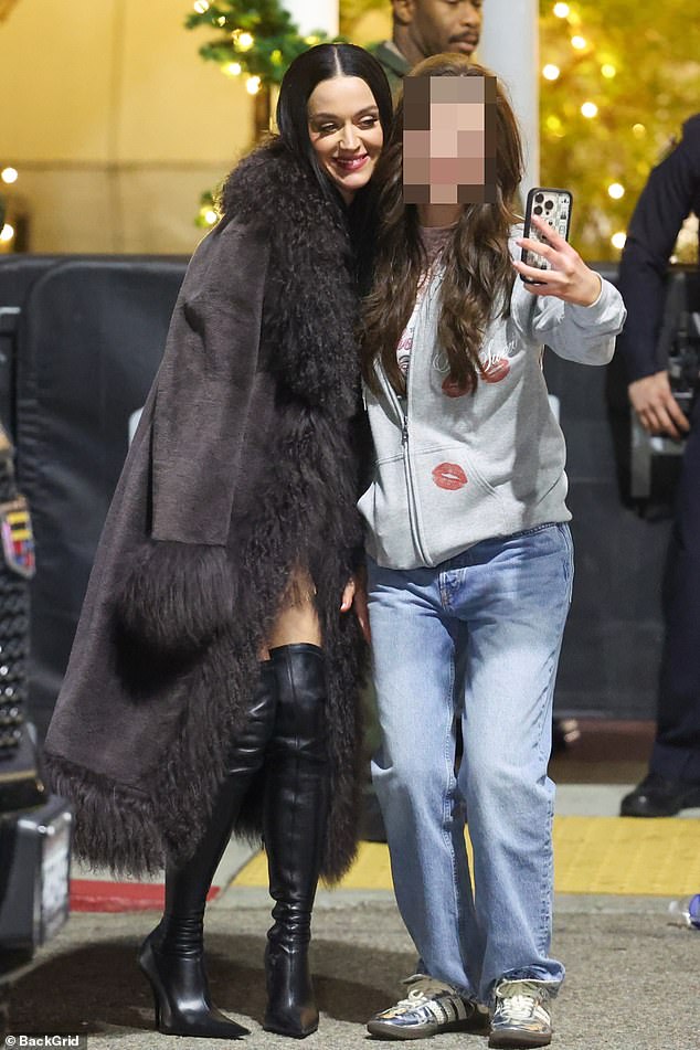 She layered the eye-popping outfit with a long faux sheepskin coat and posed with fans outside the arena