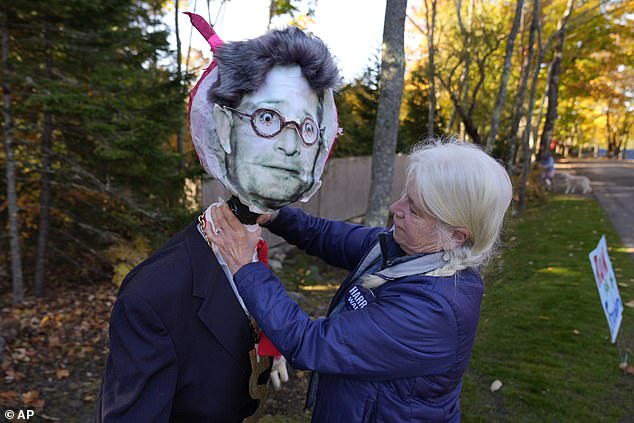 Caroline Pryor adjusts the head of a mannequin bearing an image of Leonard Leo during a protest