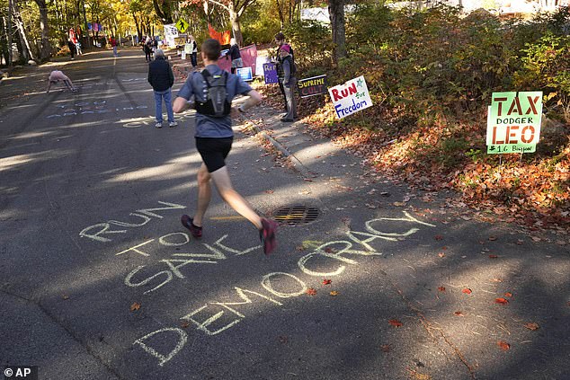 Messages are written in chalk during a protest in front of the home of Leonard Leo during the Mount Desert Island Marathon