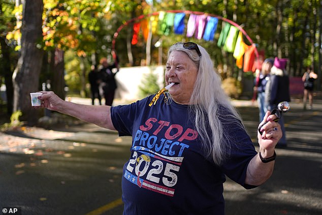 A protester holds water for runners during a protest in front of the home of Leonard Leo during the Mount Desert Island Marathon