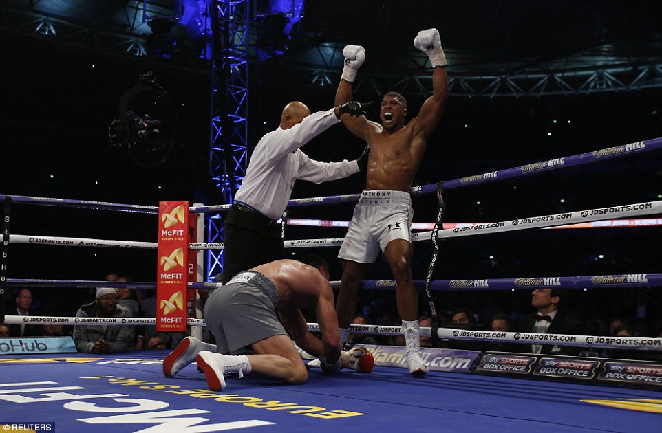 Joshua raises his fists in celebration after flooring the challenger with a brutal combination in the fifth 