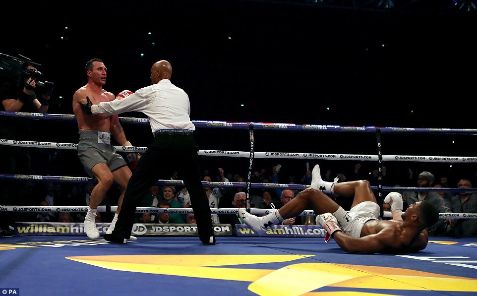 Klitschko is ushered back to his corner while Joshua lies on the canvas for the first time in his professional career