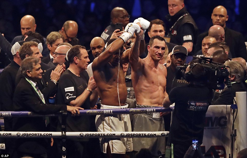 Joshua sportingly raises Klitschko's fist to the crowd after an exhausting heavyweight battle at Wembley