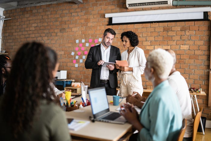 Two business people doing a meeting with the team in a coworking business office