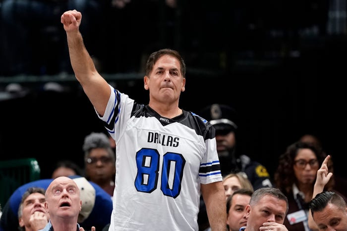 Mark Cuban is standing on the sidelines with a raised fist at a Dallas Mavericks v. Utah Jazz basketball game.