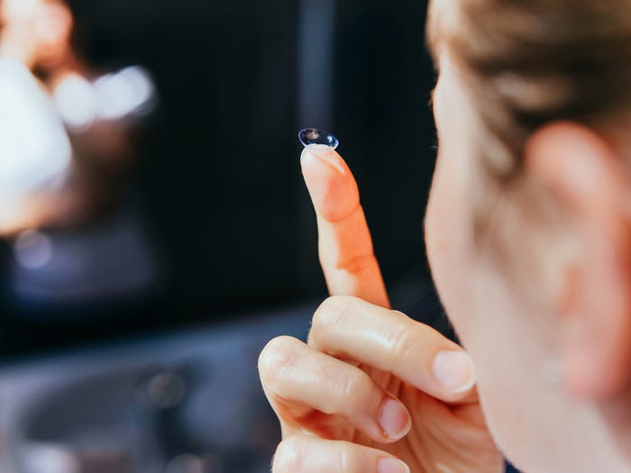 Person holding contact lens on finger