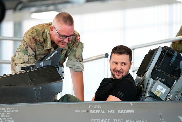 Ukrainian President Volodymyr Zelensky (R) reacts as he sits in a F-16 fighter jet in the hangar of the Skrydstrup Airbase in Vojens, northern Denmark, on August 20, 2023.