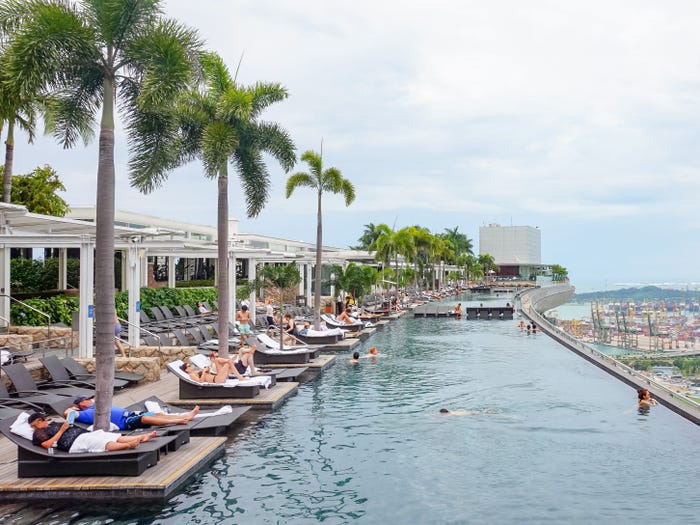 People relax at a hotel infinity pool on a cloudy day