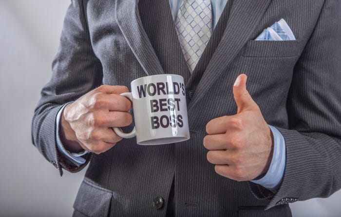 Suited man holding a mug that says "World's Best Boss" and giving a thumbs up.