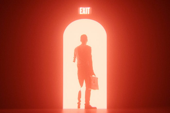 Business man leaving doorway red exit sign