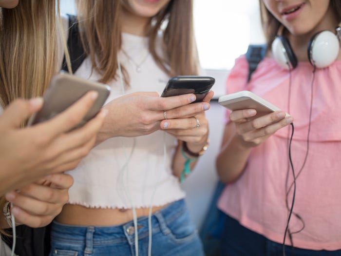 Teenage girls using cell phones in school