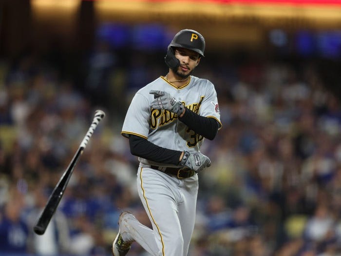 Tupacito Marcano throwing a bat in uniform with a blurry stadium in the background.