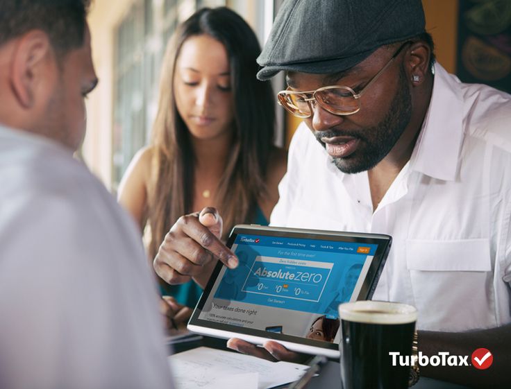 two people sitting at a table looking at a tablet