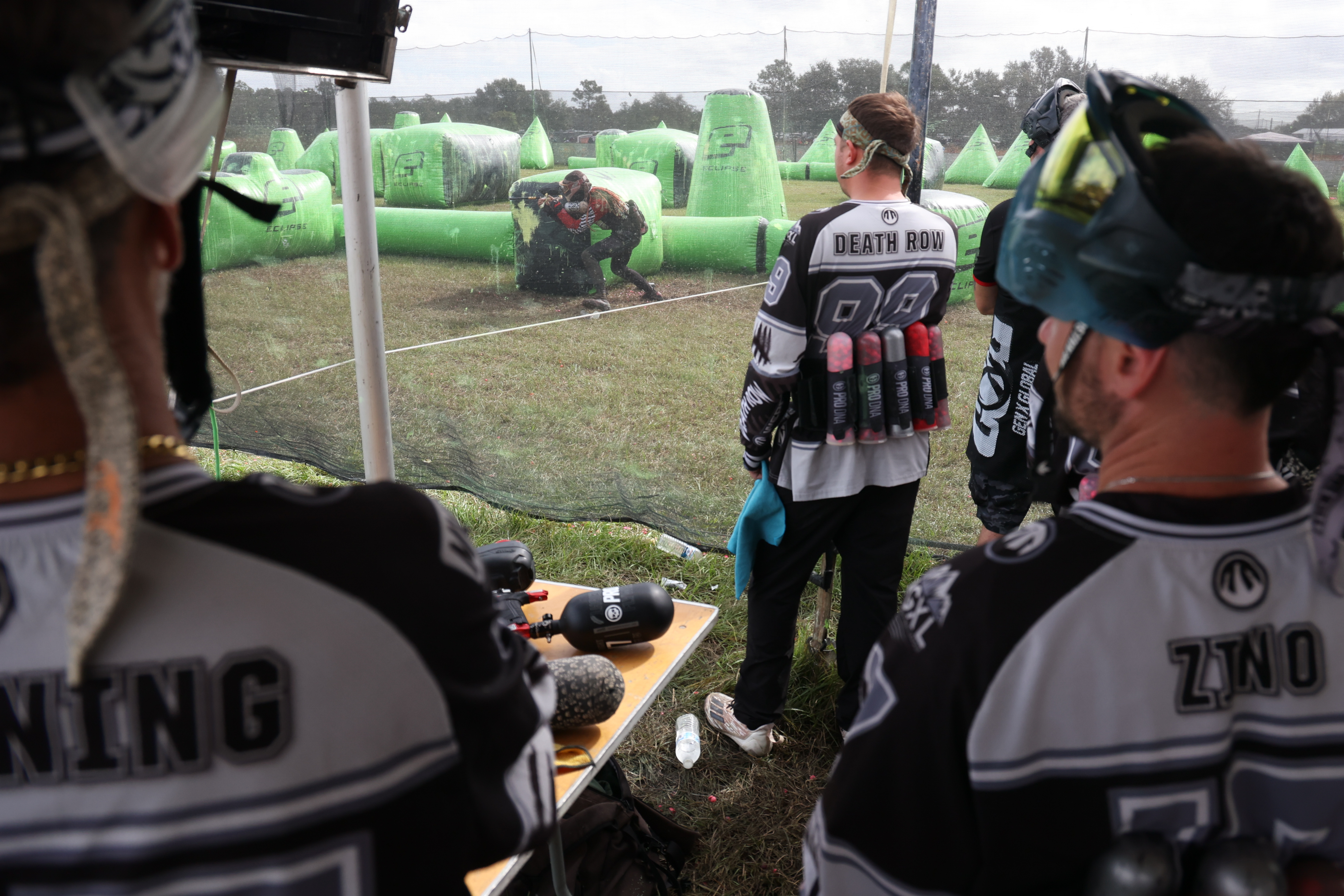 The sideline of Death Row paintball team from Palm Bay looks on as a player from the opposing LAX team takes a position to avoid a steady stream of paintballs aimed his way during a match at the NXL World Cup of Paintball on Thursday, Nov. 7, 2024. (Rich Pope, Orlando Sentinel)