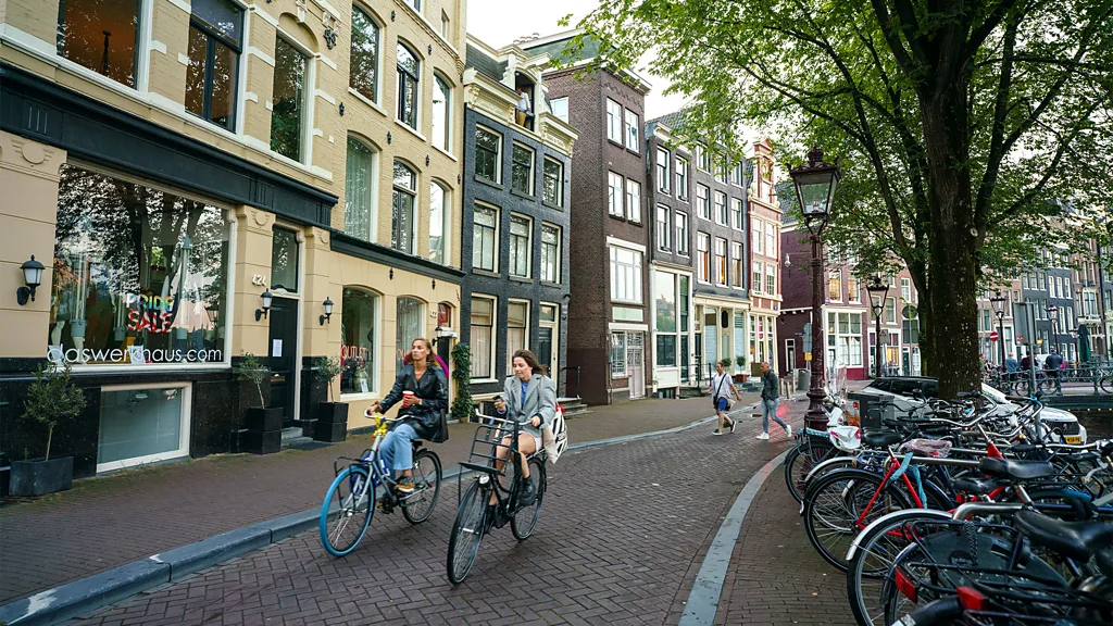 People ride bikes around streets of Amsterdam