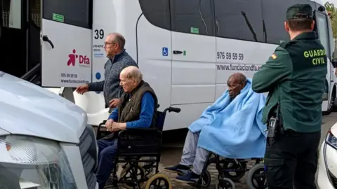 AP/Ferran Mallol Elderly people are moved from their care home after a fire at Jardines De Villafranca