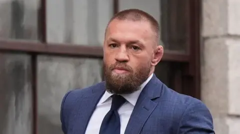 Conor McGregor leaving the High Court in Dublin on 5 November.   He has a full beard and is wearing a blue suit, navy tie and a white shirt.