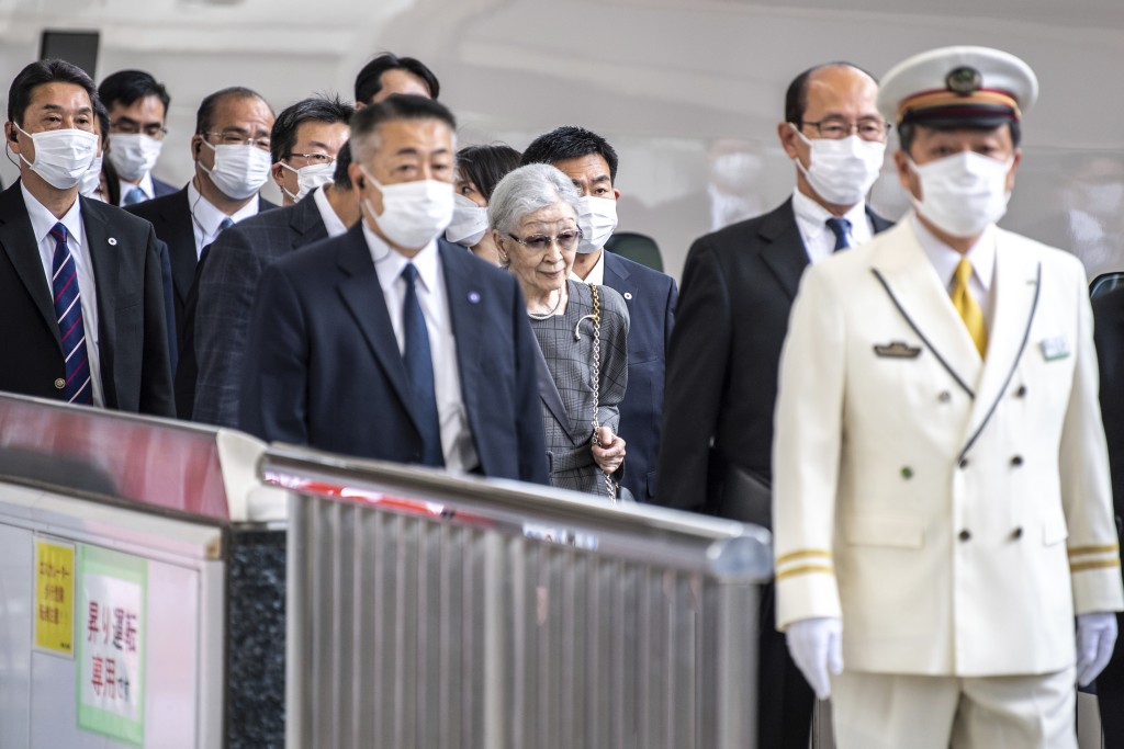 明仁與美智子上午在東京站站長等人護送下步入車廂。美聯社 