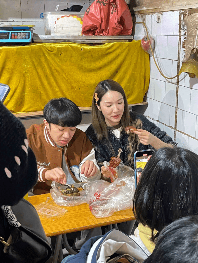 王祖男正在吃地道的田螺，李亞男則疑似吃燒雞。