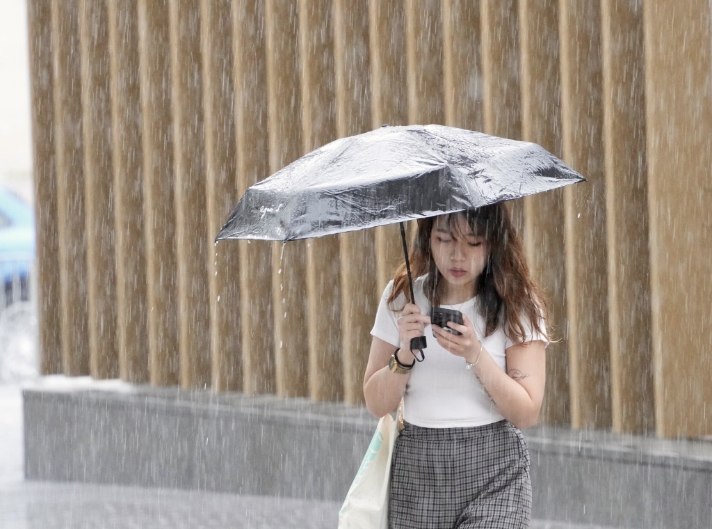 市民持雨傘遮風擋雨。蘇正謙攝