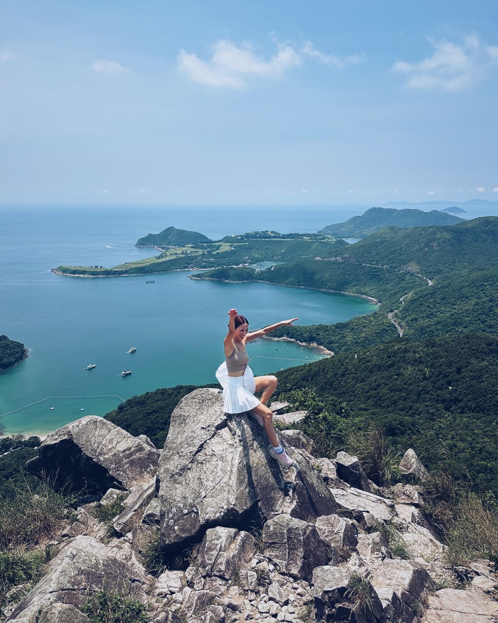 陳凱琳站在山峰嶙峋的石尖上，舉起雙手拍照。