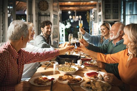 Kurioser Schnaps: Eine Familie sitzt am Weihnachtstisch und stößt an.