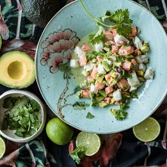 Ceviche mit Lachs peruanische Art auf einem Teller mit Avocados und Limetten daneben