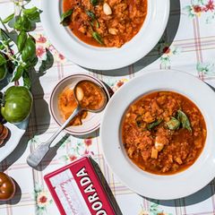 Tomatensuppe angerichtet neben frischen Tomaten