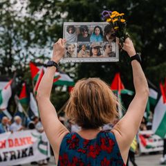 Karoline Preisler hält ein Schild mit Gesichtern bei einer Pro-Palästina Demo hoch