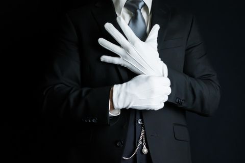 Ein Butler zieht weiße Handschuhe an