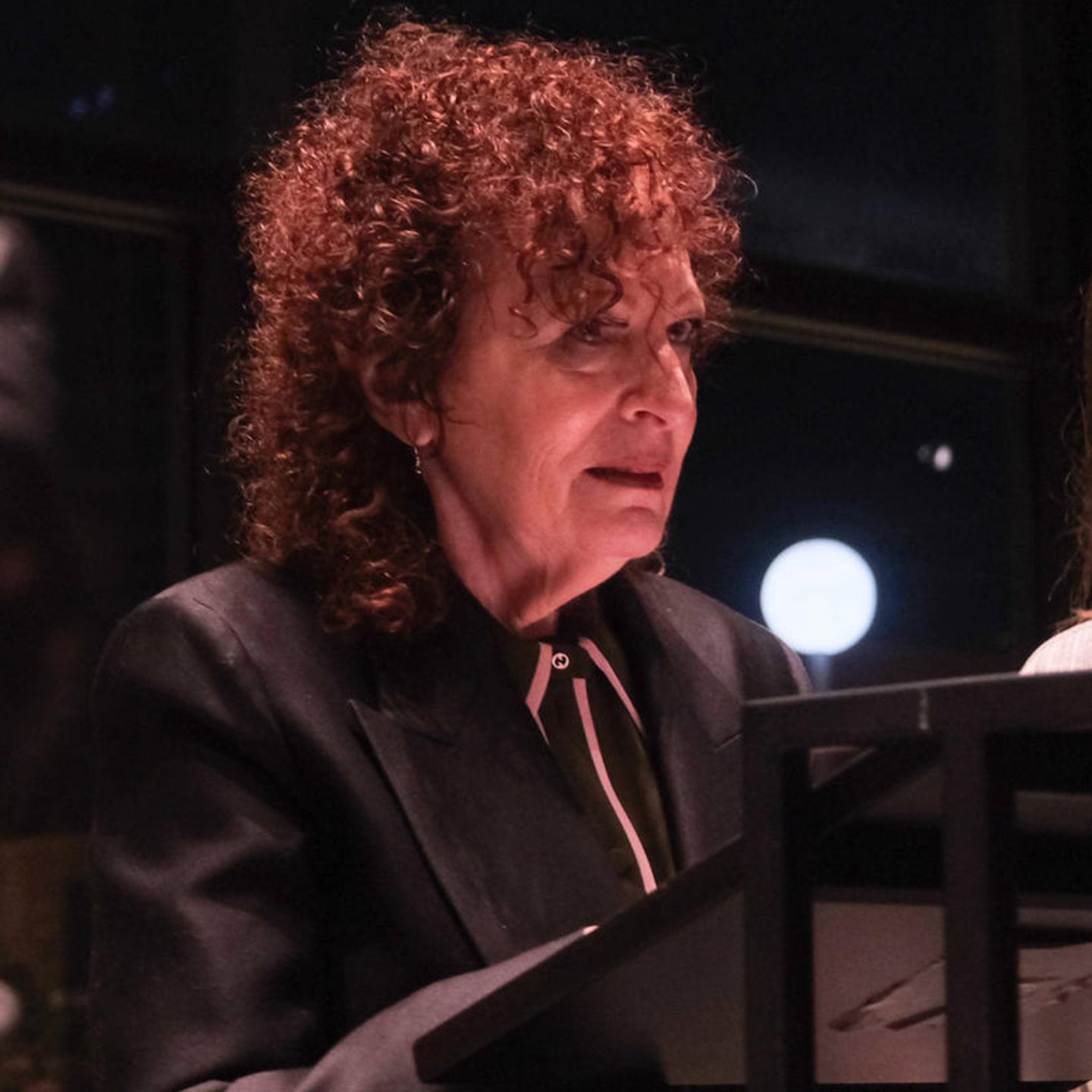 Nan Goldin steht am Redepult in der Neuen Nationalgalerie in Berlin, mehrere Leute halten Handys hoch und filmen sie