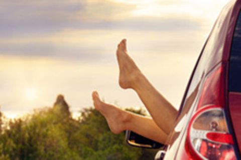 Nackte Füße werden aus dem offenen Fenster eines Autos gestreckt.