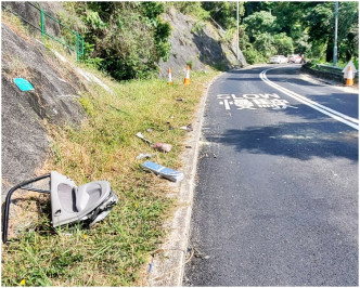 部分汽車零件殘骸散落路旁草地。