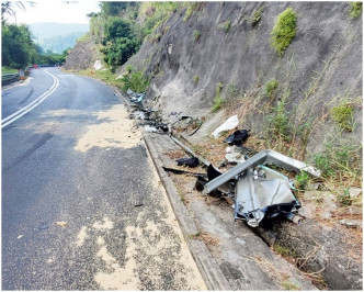 部分汽車零件殘骸散落路旁草地。