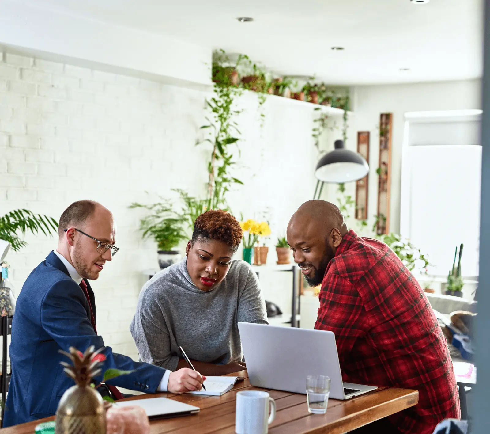 An insurance agent and two customers review an insurance policy with Docusign on a laptop