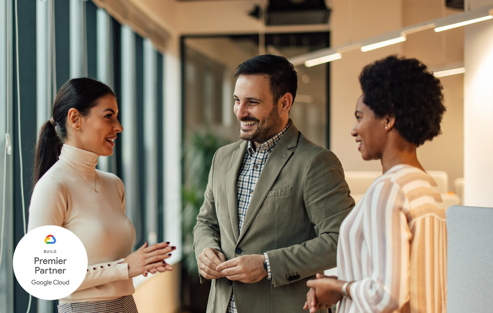 Two businesswomen and a businessman chatting in an office space.