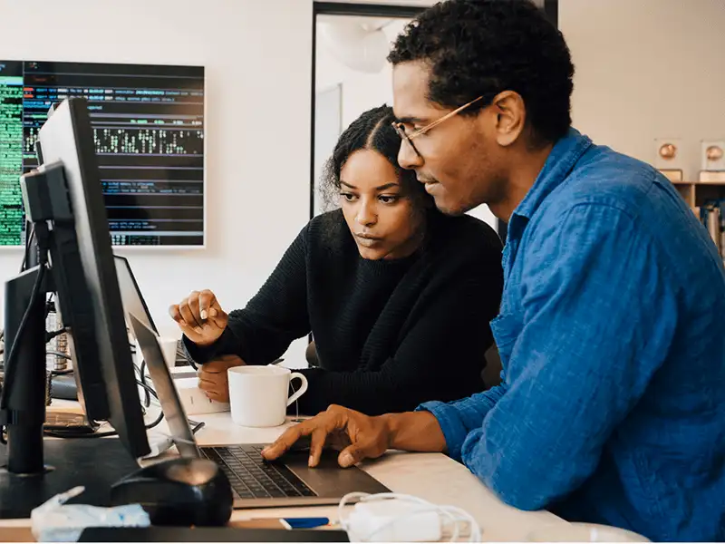 Two developers at work looking at the same computer screen