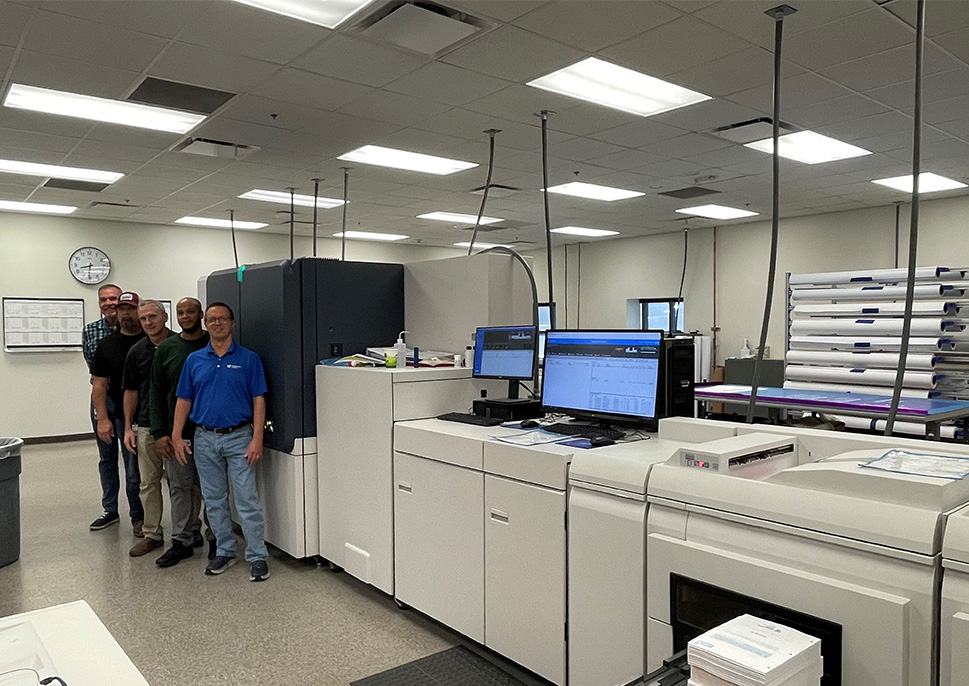 Ecompass Health workers standing in front of printer