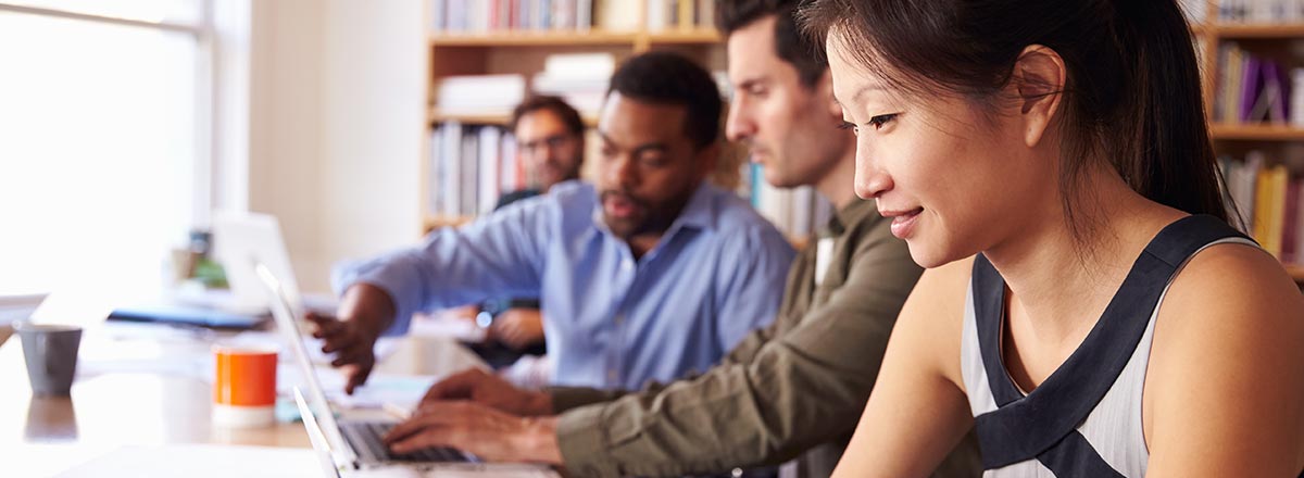 A row of professionals at a table with laptops