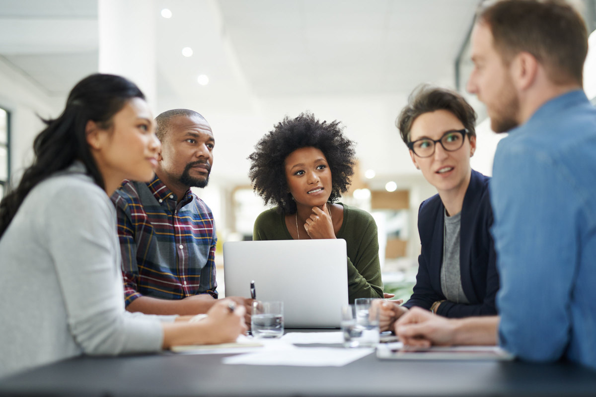 Diverse group of colleagues meeting around a laptop