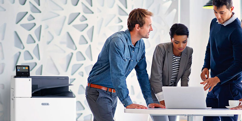 People meeting in an office around a laptop, next to a Xerox MFP