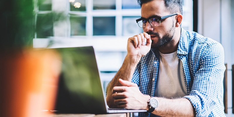 Man sitting at laptop thinking.