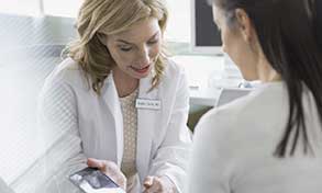 Doctor with patient, looking up records on a smartphone