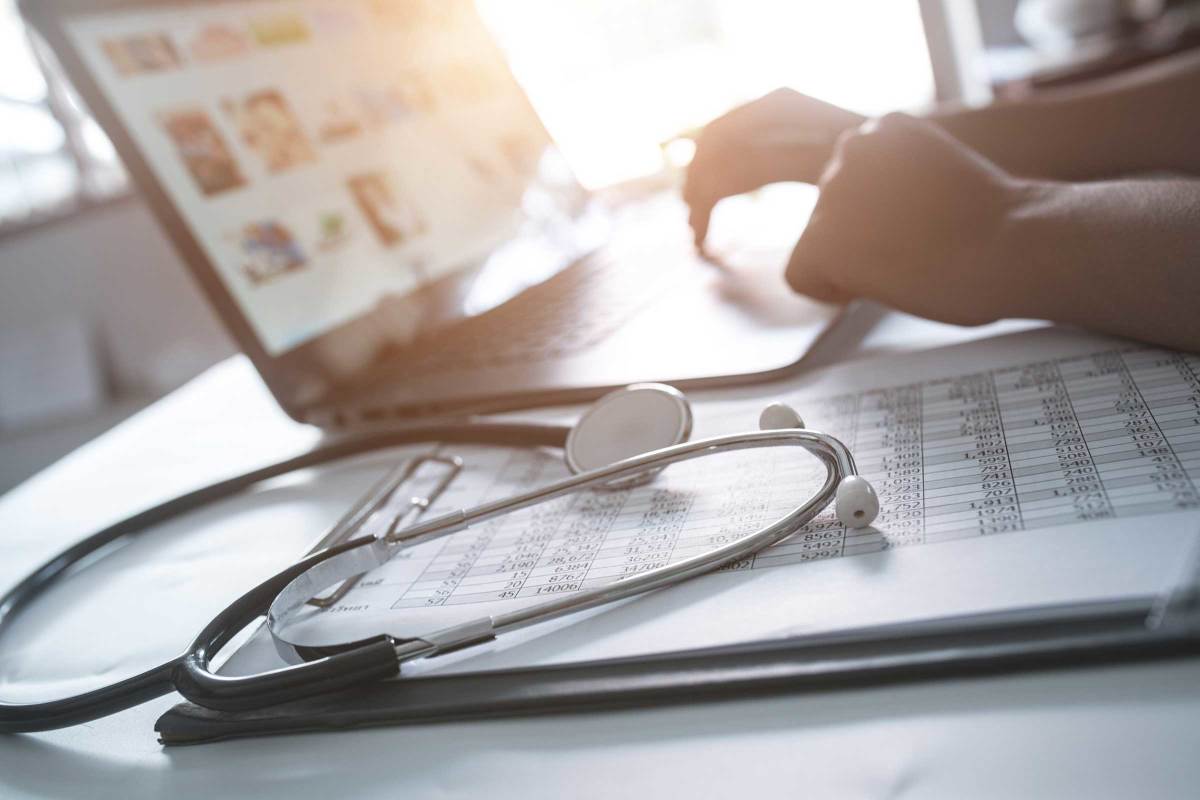 A stethoscope on a clipboard with a laptop in the background