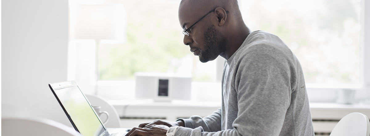 A man working on a laptop next to a window