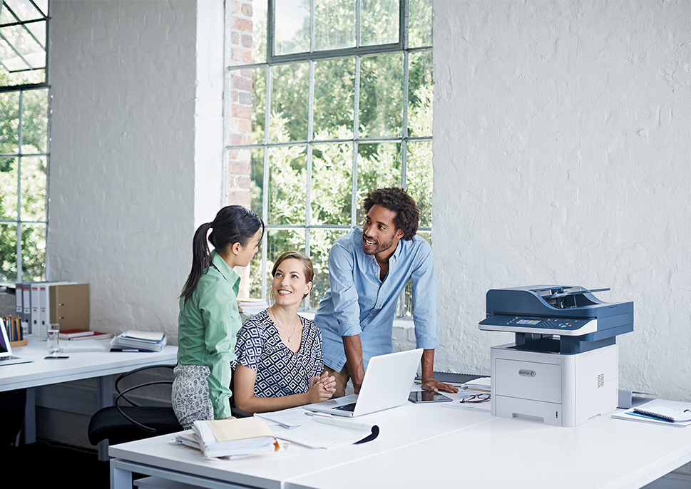 Coworkers talking next to a Xerox MFP