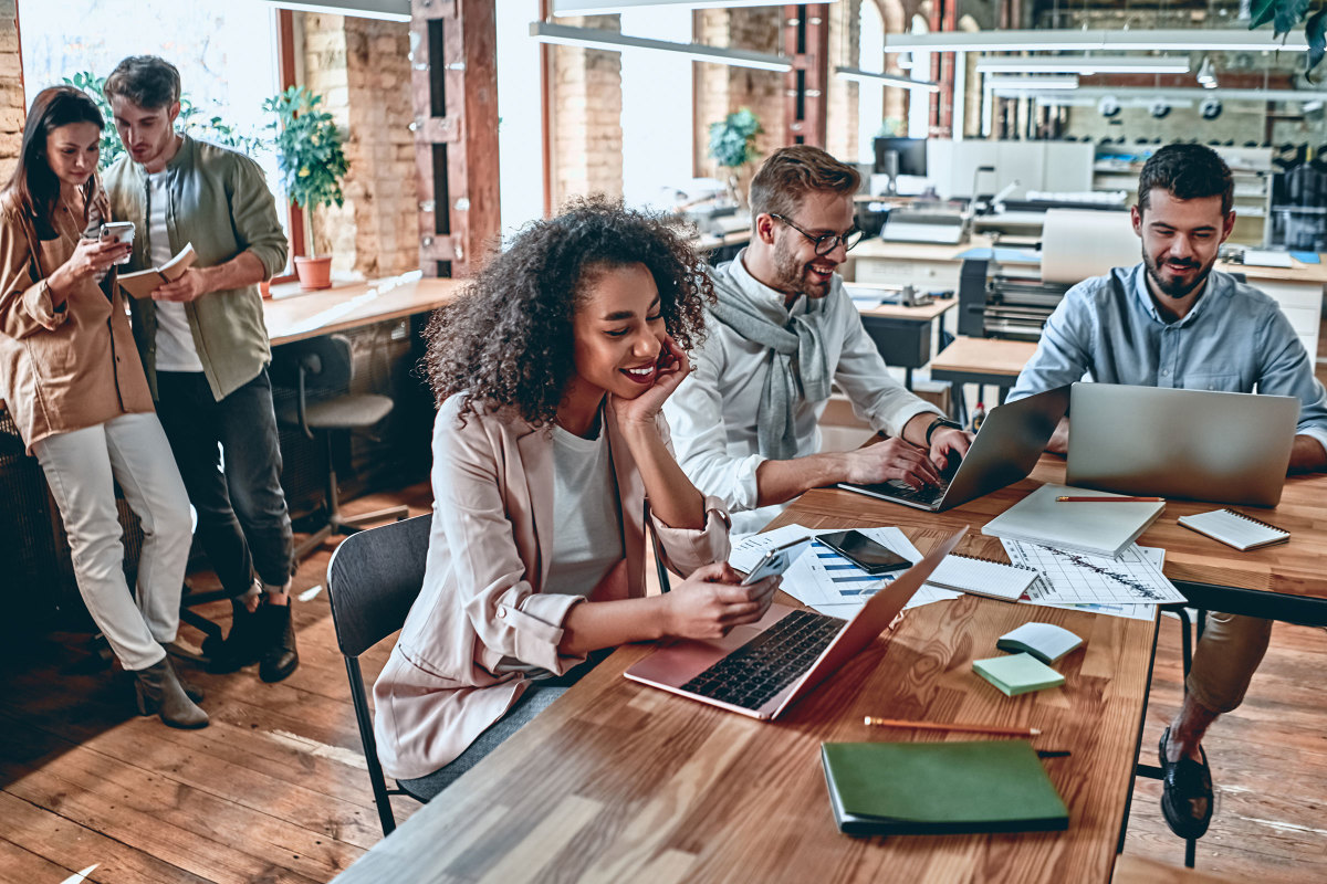 Coworkers in a wood paneled office looking at various digital devices