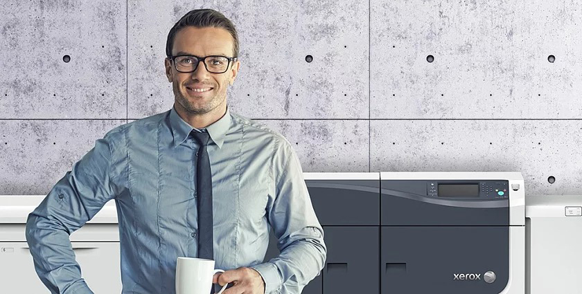 Man with coffee, standing in front of a Xerox digital press, with a colorful print sample in front of him